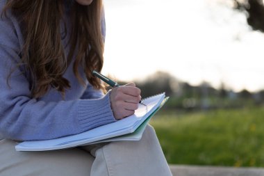 Gökte kopya alanı olan bir defterin üzerine yazı yazan bir kadının ayrıntıları