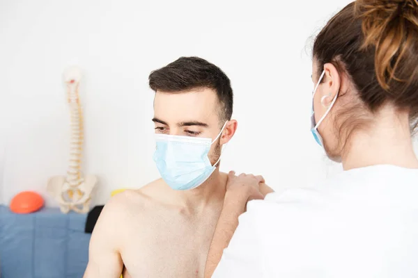 Coronavirus salgını sırasında maske takan bir hastanın rehabilitasyonu üzerinde çalışan bir fizyoterapist.