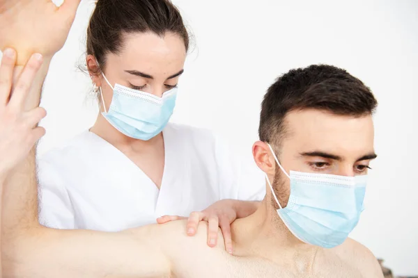 Coronavirus salgını sırasında yüz maskesi takan bir fizyoterapistin hastayı tedavi edişine yakından bakın..