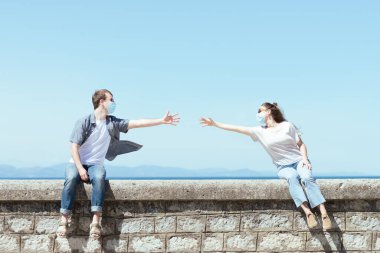 Coronavirus salgını sırasında sosyal uzaklık ve kayıp insanlar. Yüz maskesi takan ve birbirine yaklaşmaya çalışan çift..