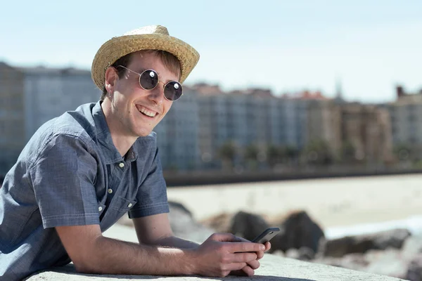 Ung Glad Leende Turist Kollar Sin Telefon Vid Kusten Stad — Stockfoto