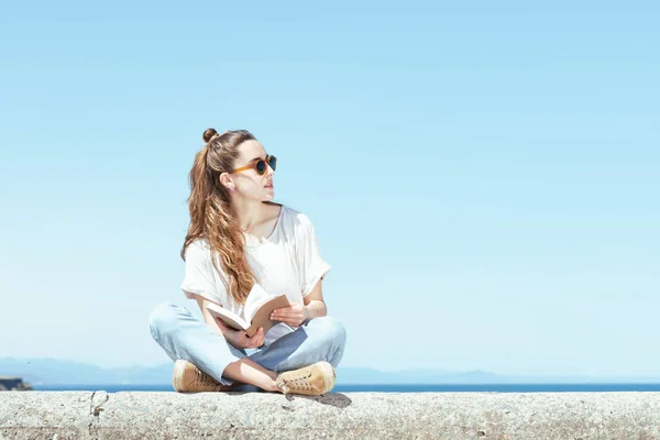 きれいな女性が本を持って石のベンチに座っている 夏の晴れた日に勉強する — ストック写真