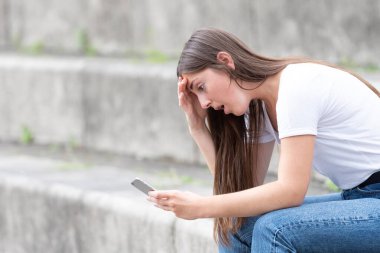 Şok olmuş genç bir kadın telefonundan kötü haberler alıyor..