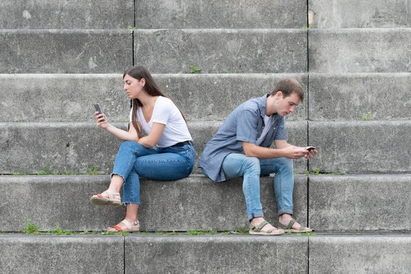 Digital and social media addiction. Young couple ignoring each other and chating on the phone.