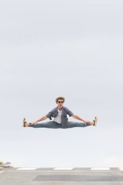 Yolda zıplayan rahat giyimli erkek dansçı. Fotokopi alanı ile mutluluk kavramı. Asfalt ve gökyüzü ile en düşük bileşim