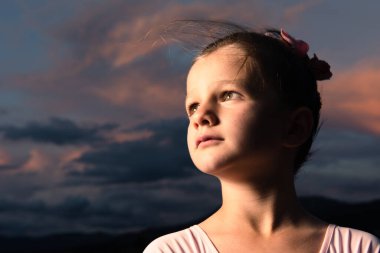 Gün batımında küçük bir balerin kızın dramatik portresi. Çocuk gelecek konseptini hayal ediyor.