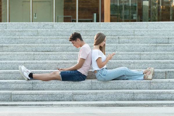 数码成瘾的Z代青少年的概念 坐在楼梯上的年轻夫妇都集中在手机和社交媒体上 — 图库照片