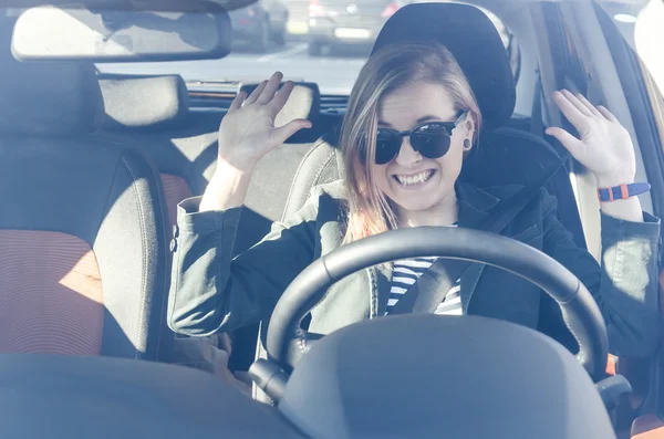 Atractiva mujer sentada en el asiento del conductor en el coche con las manos arriba —  Fotos de Stock