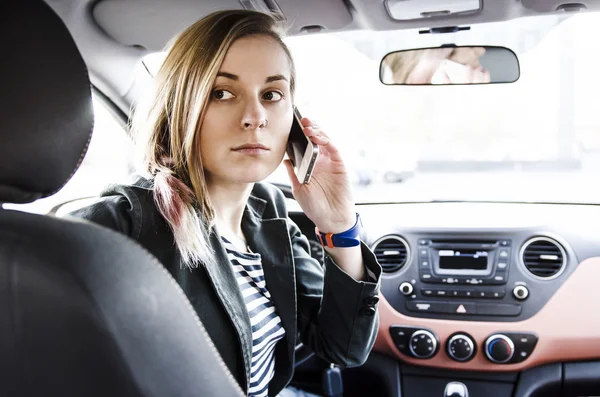 Attraktive Frau sitzt im Auto und hält Telefon — Stockfoto