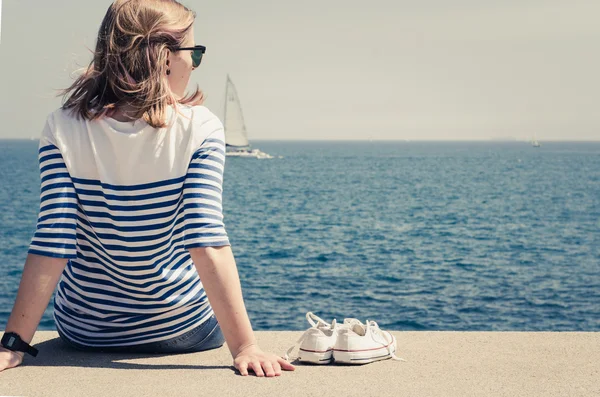Mulher hipster sentado na fronteira rodoviária e olhando para a frente na vista do mar . — Fotografia de Stock