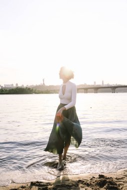 Güzel genç bir kadın sahilde poz veriyor ve dans ediyor.