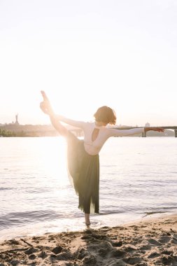 Güzel genç bir kadın sahilde poz veriyor ve dans ediyor.