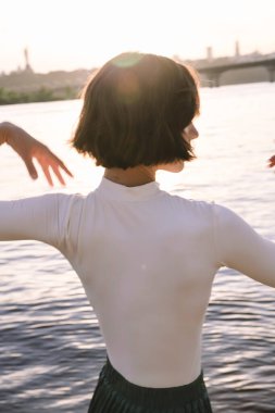 Gün batımında sahile yakın poz veren genç kadın portresi.