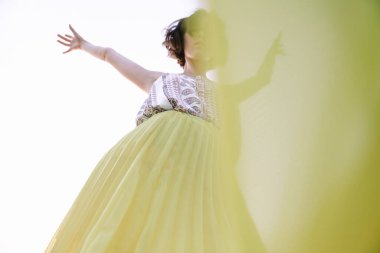 Sarı etekli kadın dans ediyor ve poz veriyor.