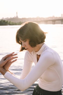 Gün batımında sahile yakın poz veren genç kadın portresi.