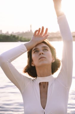 Gün batımında sahile yakın poz veren genç kadın portresi.