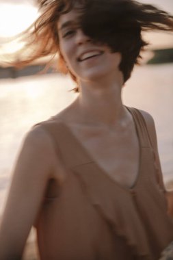 Mutlu genç bir kadın gün batımında gülümsüyor ve mutlu hissediyor.