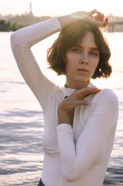 Gün batımında sahile yakın poz veren genç kadın portresi.