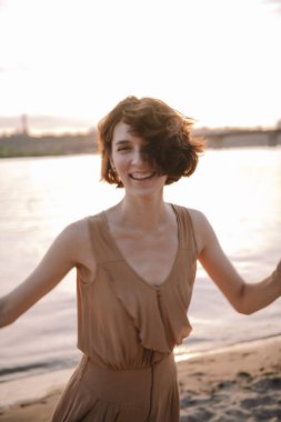 Mutlu genç bir kadın gün batımında gülümsüyor ve mutlu hissediyor.