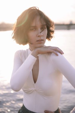 Gün batımında sahile yakın poz veren genç kadın portresi.