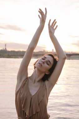 Gün batımında genç bir kadın poz veriyor ve yoga yapıyor.