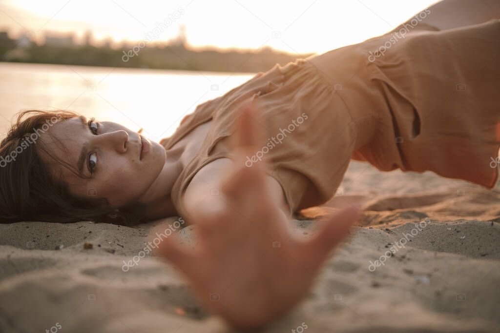 young woman posing and yoga dancing near beach at sunset