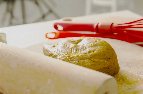 Beautiful kitchen with red tablecloth, rolling pin and dough for biscuit cake. — Stock Photo, Image