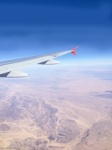 Top view from plane window to desert through clouds. View to sky. — Stock Photo, Image