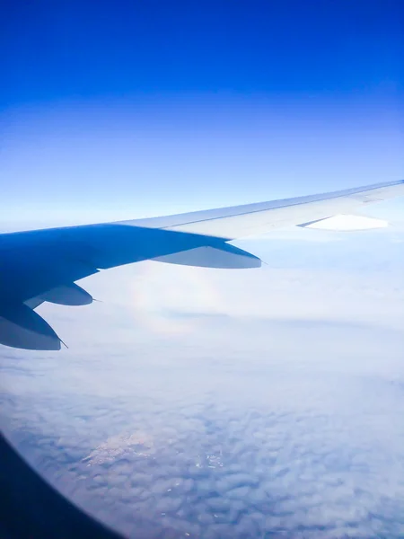 Widok z góry z okna samolotu na pustyni przez chmury. Widok na niebo. — Zdjęcie stockowe