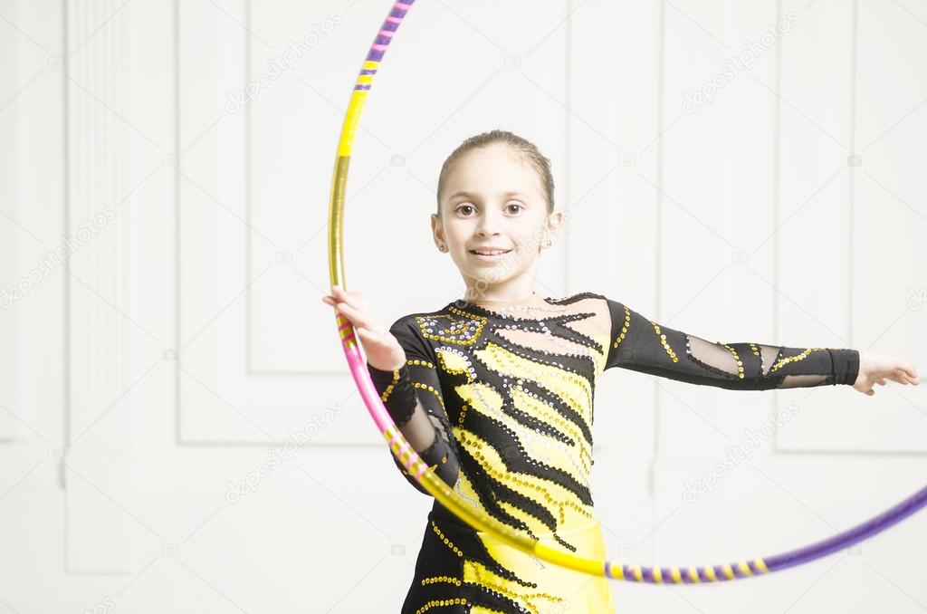 girl in leotard rolling gymnastics hoop