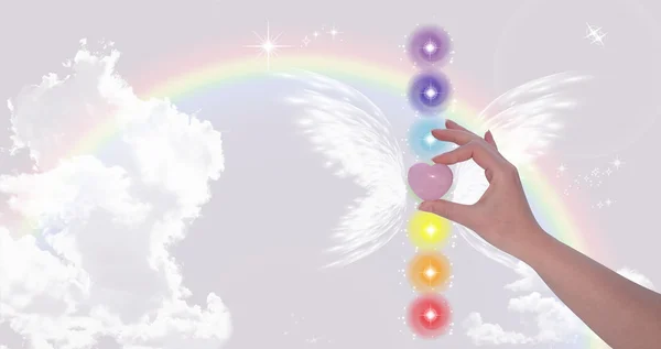 Rose kuvars kalp ve yedi çakralar tutan el