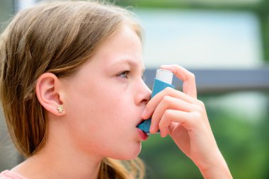 Kız bir inhaler astım krizi sırasında kullanır.