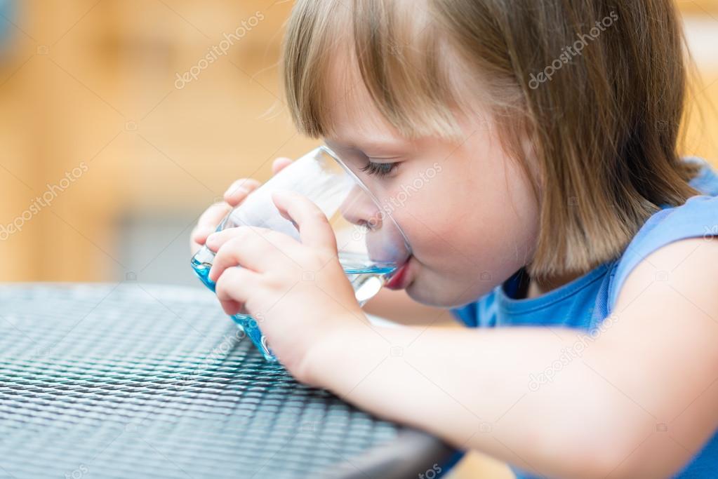 Girl drinking water. Cute little girl drinking water outdoors - very shallow depth of field