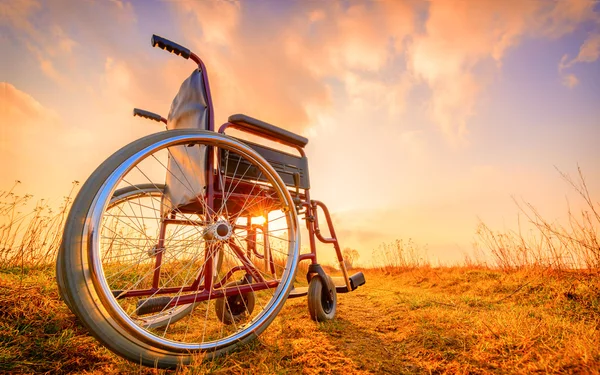 Silla de ruedas vacía en el prado al atardecer —  Fotos de Stock