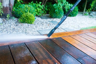Terası elektrikli çamaşır makinesiyle temizliyor. Tahta teras yüzeyindeki yüksek su basıncı temizleyicisi.