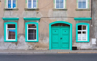 Polonya 'nın güneyinde bir yerde yeşil kapıları ve pencereleri olan terk edilmiş eski beyaz bir ev.