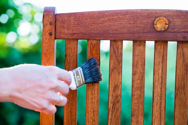 Woman Hand Holding Brush Applying Varnish Paint Wooden Garden Chair Stockfoto