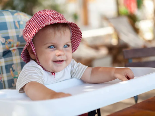Kırmızı Şapkalı Bebek Beslenme Koltuğunda Oturan Küçük Tatlı Kız — Stok fotoğraf