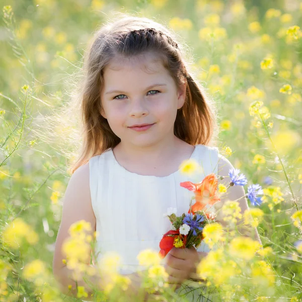 Linda niña en un prado con flores silvestres de primavera — Foto de Stock