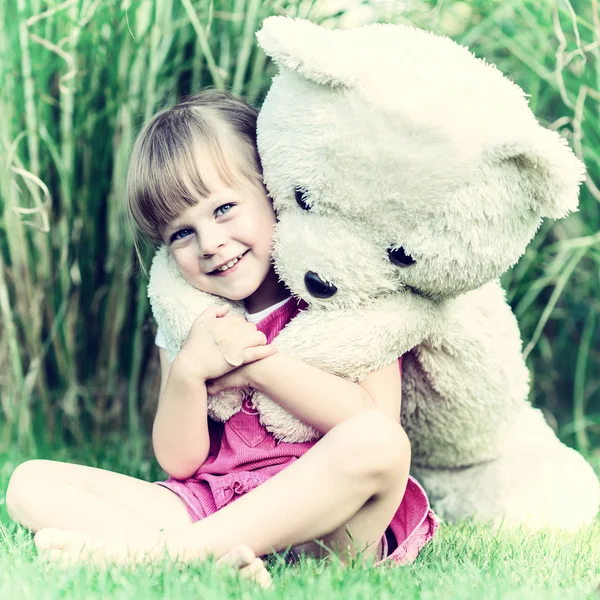 Vintage foto de una chica sentada en la hierba con gran peluche ser —  Fotos de Stock