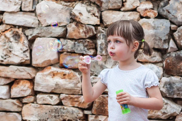 Мила маленька дівчинка дме мильні бульбашки — стокове фото