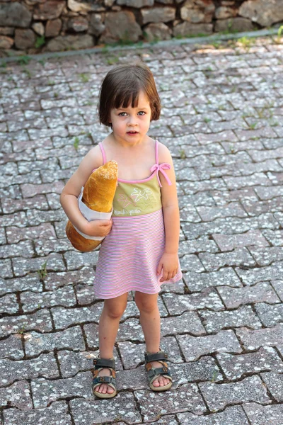 Adorable little girl holding  a loaf of bread — Stock Photo, Image