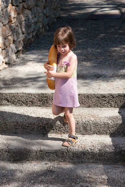 Очаровательная маленькая девочка держит буханку хлеба — стоковое фото