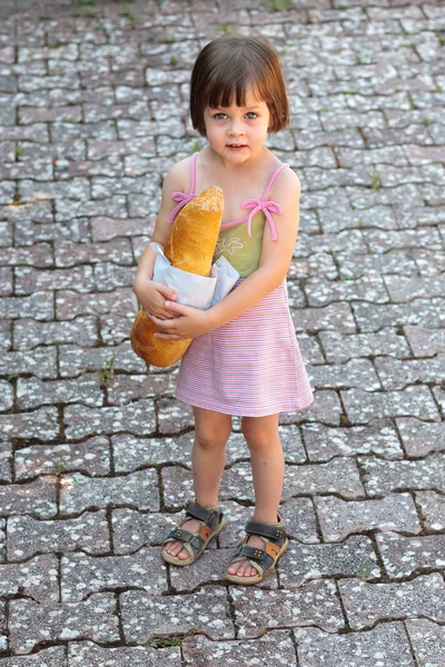 Adorable niñita sosteniendo una barra de pan —  Fotos de Stock