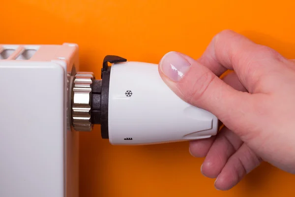 Radiator thermostat and hand - orange — Stock Photo, Image