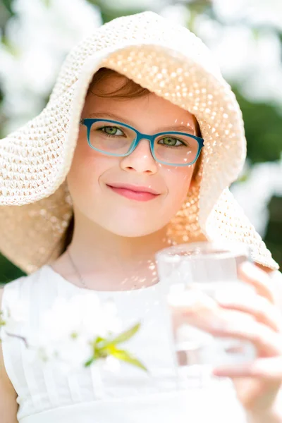 Zomer meisje in stro hoed drinkwater buiten portret. — Stockfoto