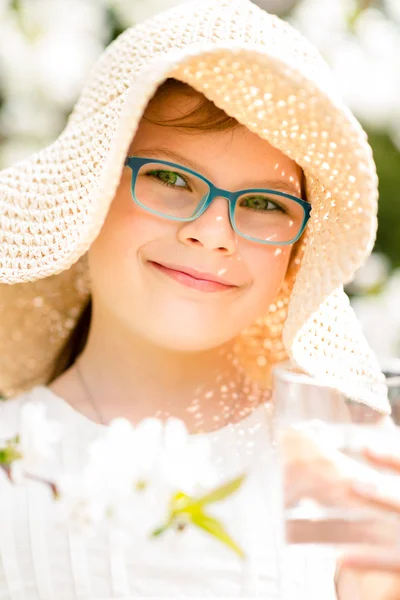 麦わら帽子の飲料水の屋外のポートレートの夏少女. — ストック写真