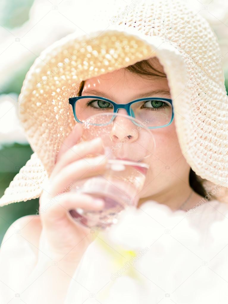 Summer little girl in straw hat drinking water outdoor portrait.