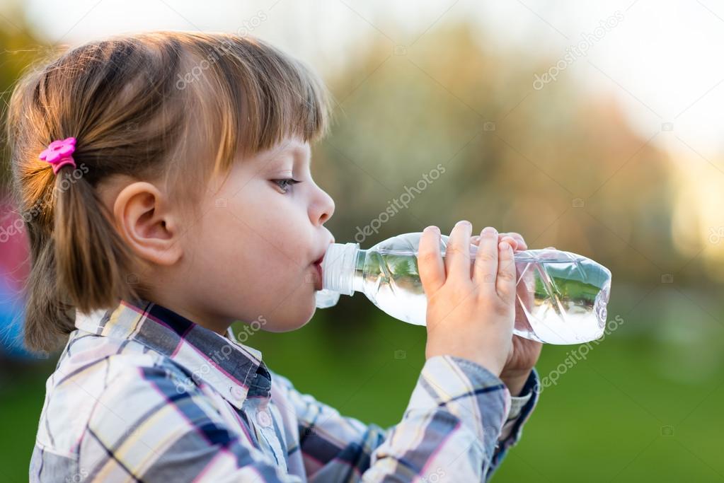 Portrait of little girl drinking water outdoor