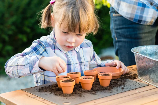 Mädchen pflanzt mit ihrer Mutter Blumensamen in Töpfe — Stockfoto